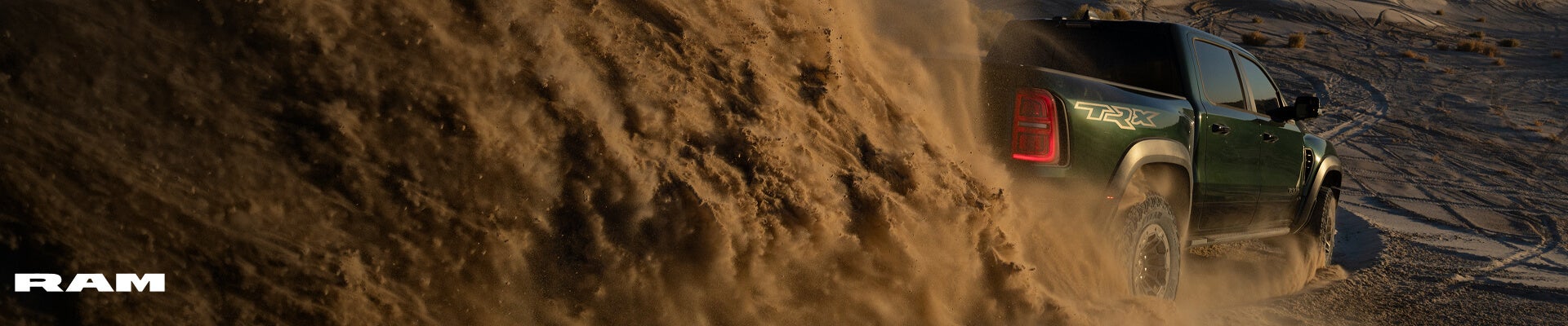 Rear view of a 2027 Ram 1500 TRX SRT in Serrano Green drifting through desert sand dunes.