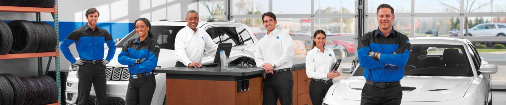 Several MOPAR CDJR Certified Technicians standing in a row in a CDJR Service Center.